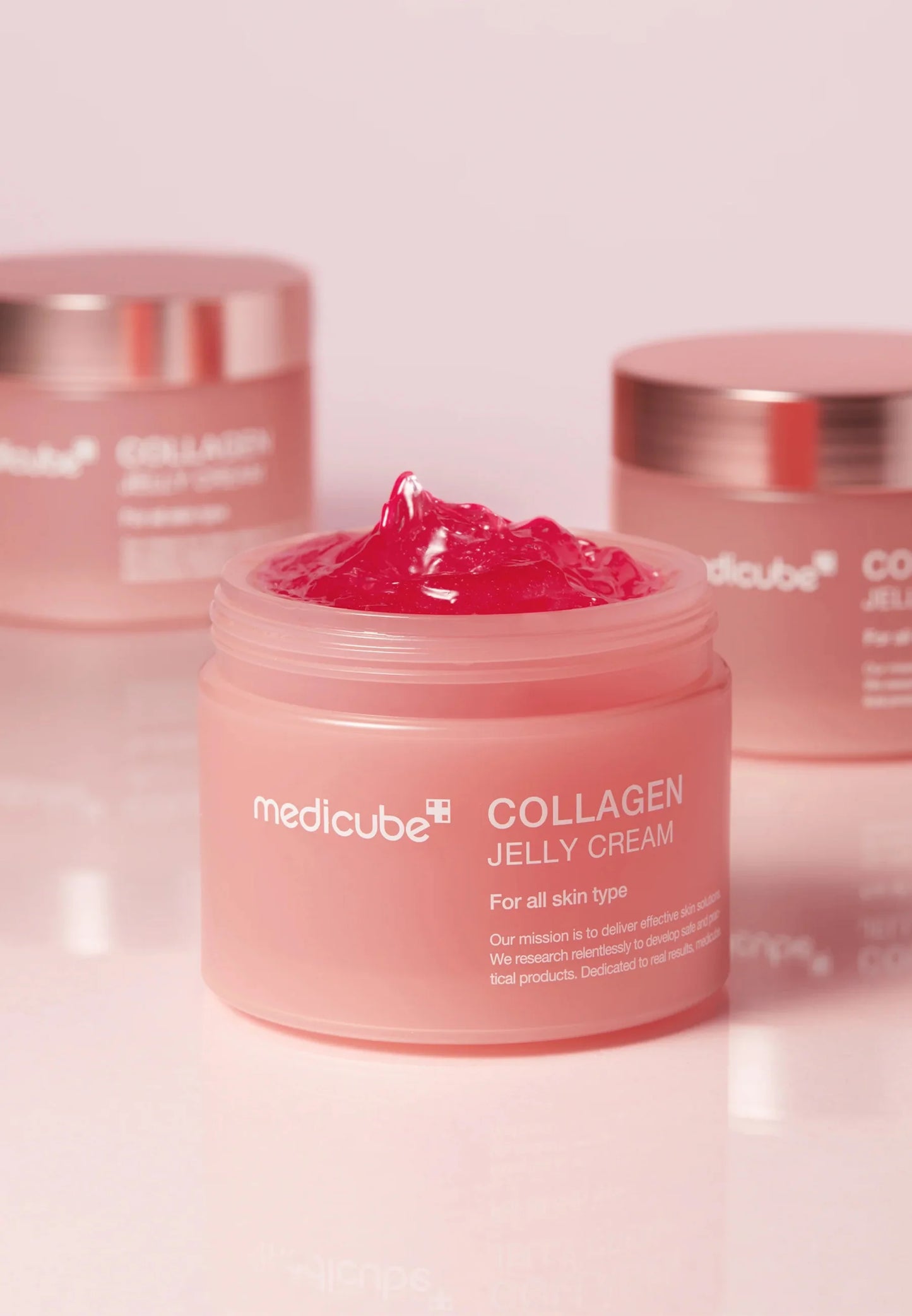 Öppen burk med Medicube Collagen Jelly Cream 110 ml med rosa gelkräm och burkar i bakgrunden.