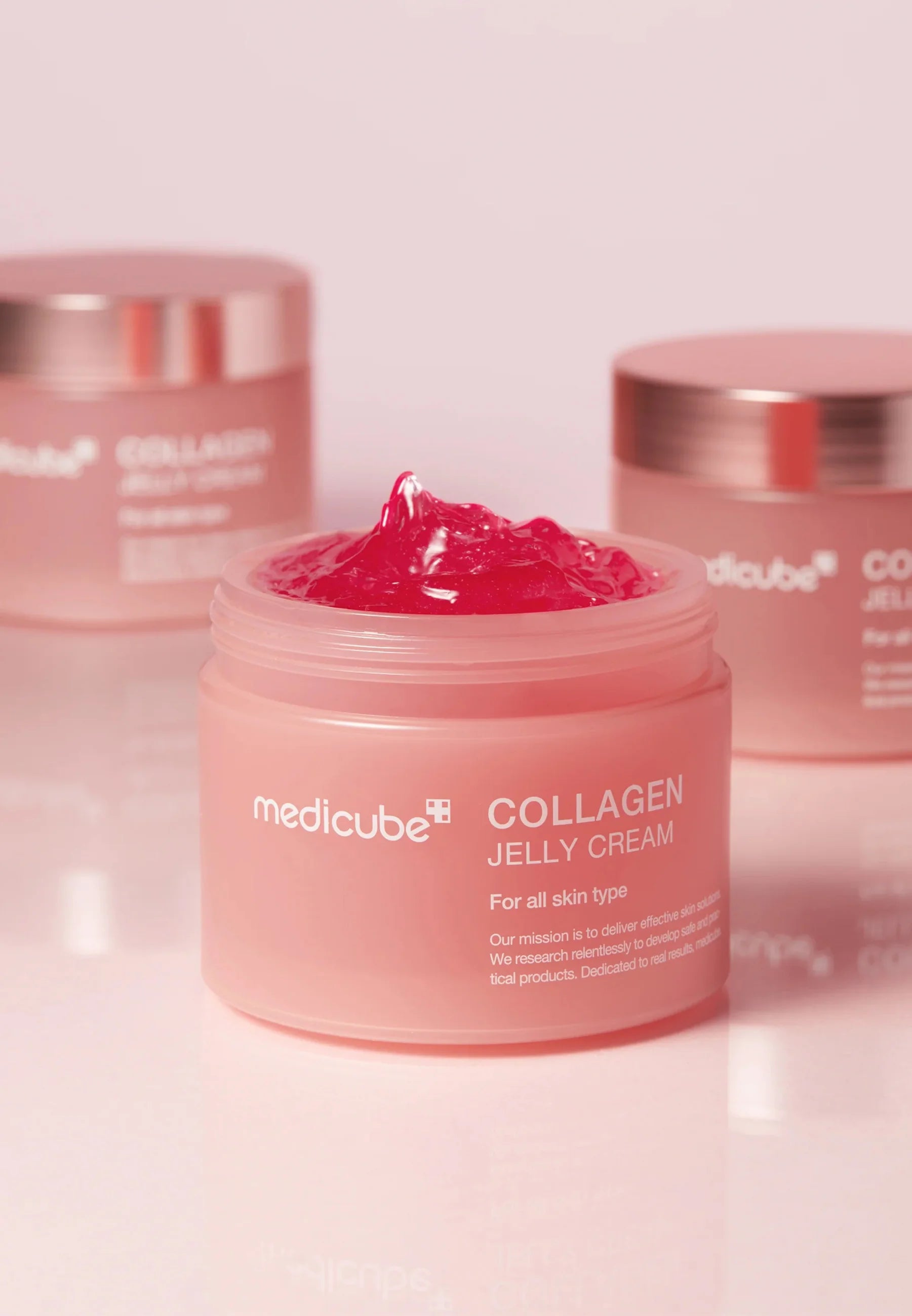 Öppen burk med Medicube Collagen Jelly Cream 110 ml med rosa gelkräm och burkar i bakgrunden.