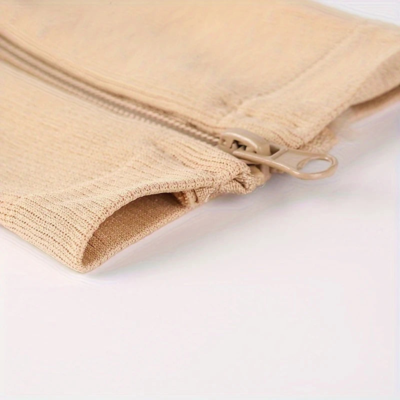 Närbild på dragkedjan och öppningen på beige stödstrumpor, visar enkel på- och avtagning.